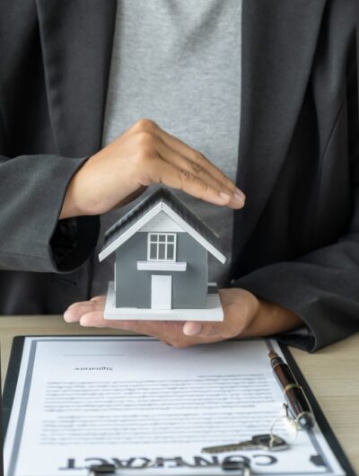 real estate agent hand prevent the home model and explain the business contract or home insurance real estate agent hand prevent the home model and explain the business contract or home insurance